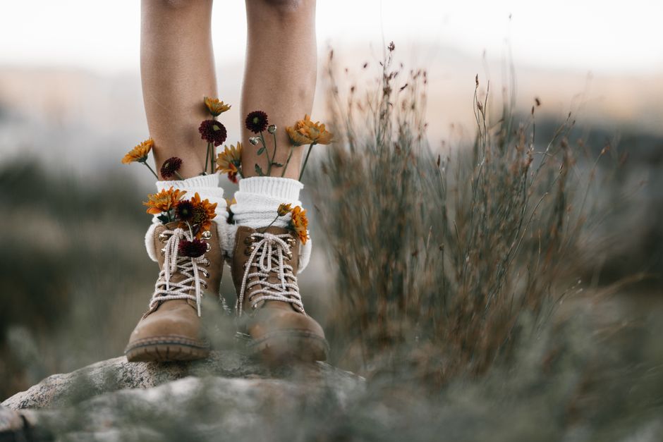 Brown boots adorned with vibrant wildflowers in a natural setting, showcasing a blend of nature and fashion.