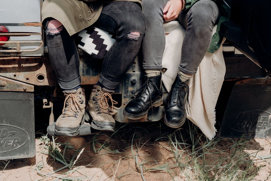 Two people sitting on a vehicle with rugged boots, ready for adventure in the outdoors.