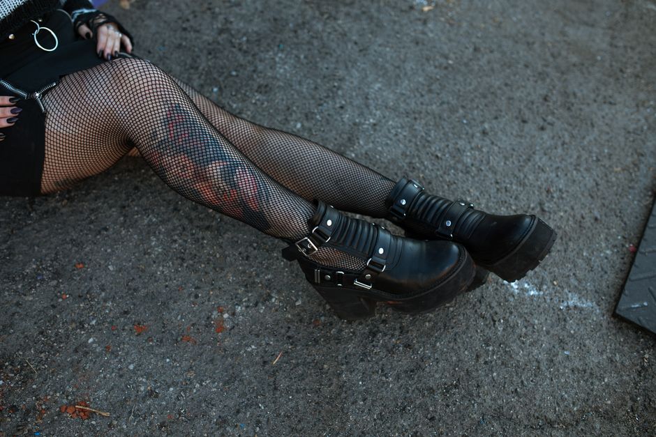 Close-up of a person's legs in fishnet stockings and black boots, showcasing edgy street style.