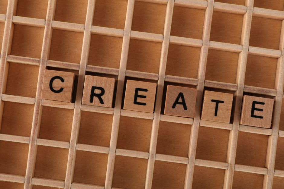 Wooden blocks in a grid forming the word CREATE, conveying creativity and innovation.