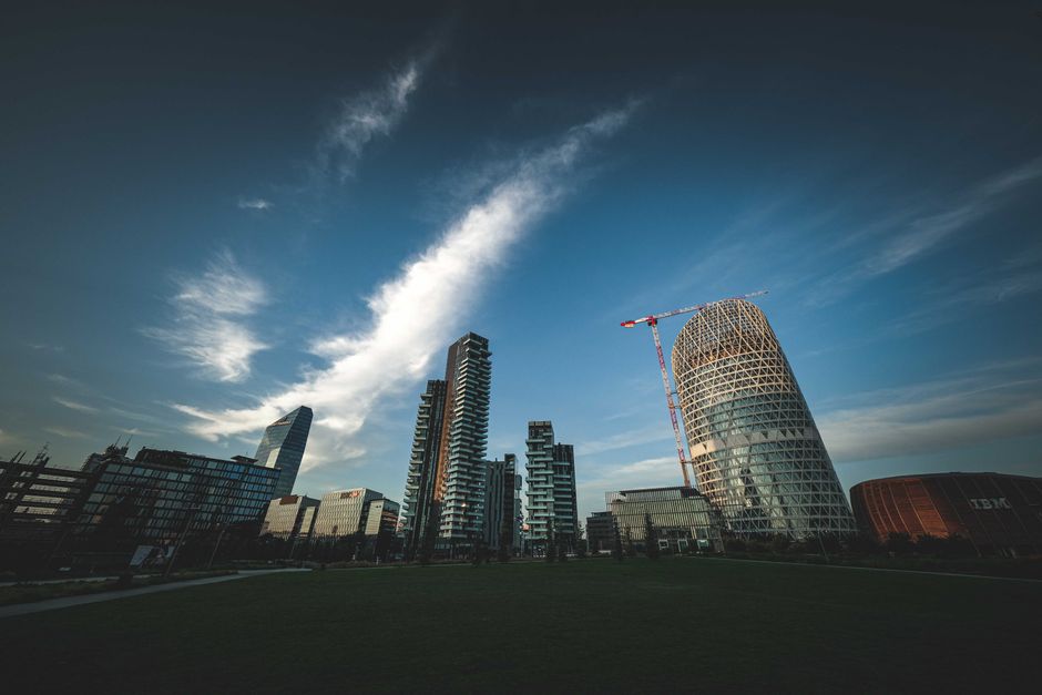 Low-angle view of unique skyscrapers and modern architecture against a clear blue sky.