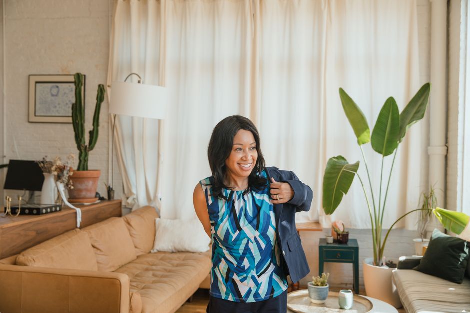 Smiling businesswoman in a cozy home office setting with modern decor, exuding confidence and style.
