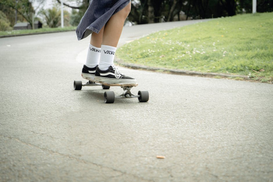 A person wearing sneakers rides a skateboard on a winding outdoor path.