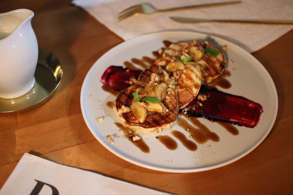 Close-up of gourmet pancakes with syrup and banana on a wooden table, perfect for breakfast.