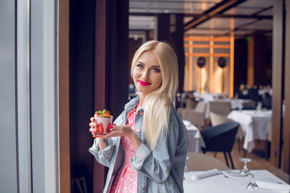 Blonde woman in a chic Parisian restaurant savouring a stylish dessert.