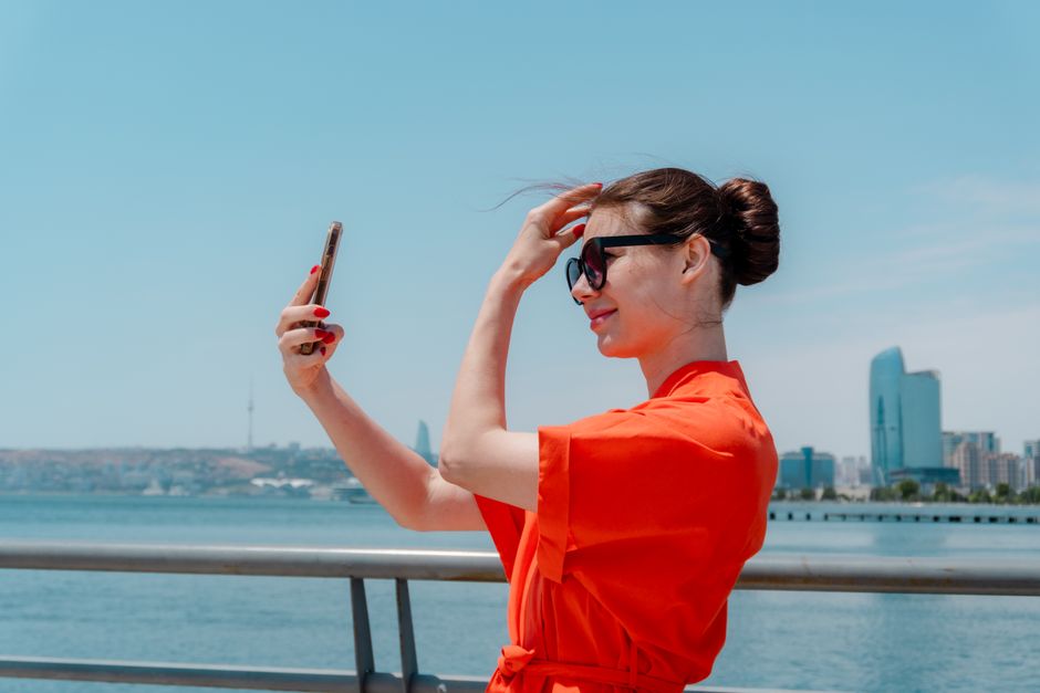 Woman in a red top trying sunglasses by the waterfront